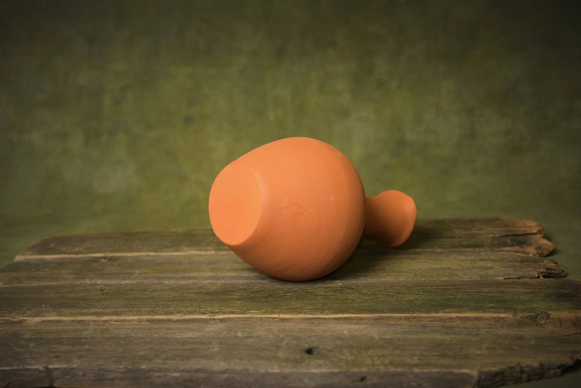 Handmade terracotta pitcher on rustic wooden surface, artisan clay homeware product