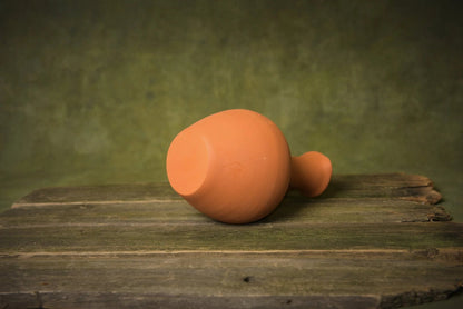 Handmade terracotta pitcher on rustic wooden surface, artisan clay homeware product