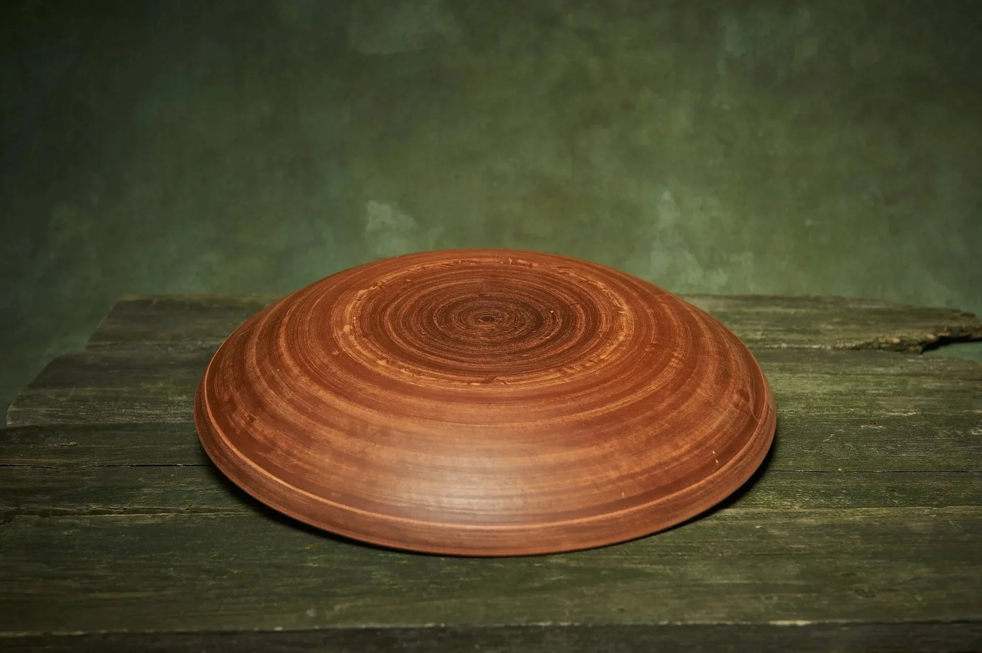 Handmade large ceramic plate with brown swirl pattern, artisan pottery, on rustic wood surface