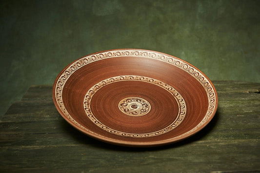 Large handmade ceramic plate with ornate patterns, artisan pottery on rustic wooden table