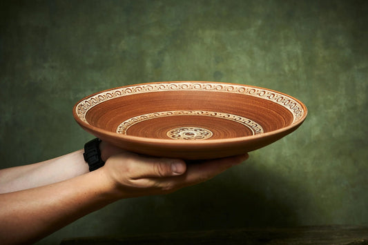 Hand holding large handmade ceramic plate with ornate rim, artisan pottery from clayproductsshop