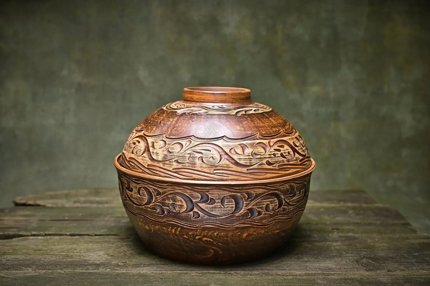 Handmade Ukrainian ceramic pot with lid, rustic carved clay casserole dish on wooden surface