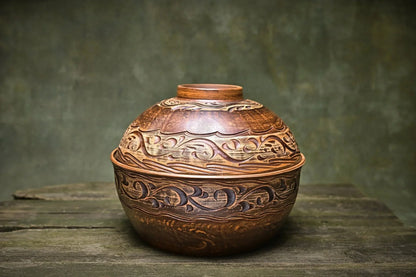 Handmade Ukrainian ceramic pot with lid, rustic carved clay casserole dish on wooden surface