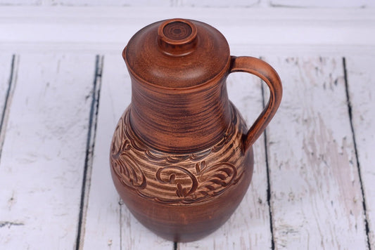 Handmade clay jug with lid, ceramic vessel with handle, rustic floral engraving