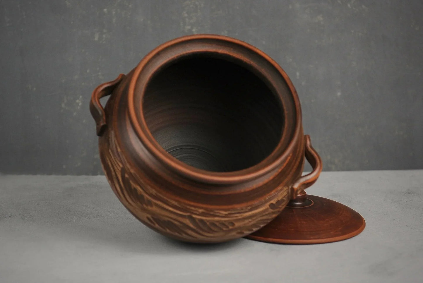 Handmade clay casserole pot with lid and handles, artisan ceramic bakeware on gray background