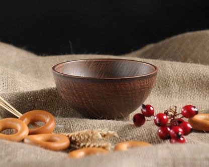 Handmade brown ceramic clay bowl on burlap with bagels and red berries, artisan pottery homeware