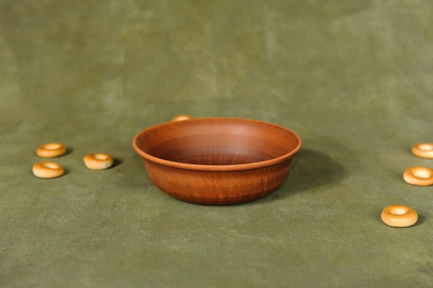 Handmade brown ceramic clay serving bowl on green surface, artisan pottery homeware