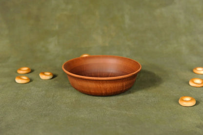 Handmade brown ceramic clay serving bowl on green surface, artisan pottery homeware