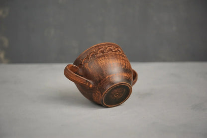 Handmade brown ceramic bowl with two handles, artisan Ukrainian pottery on a gray background