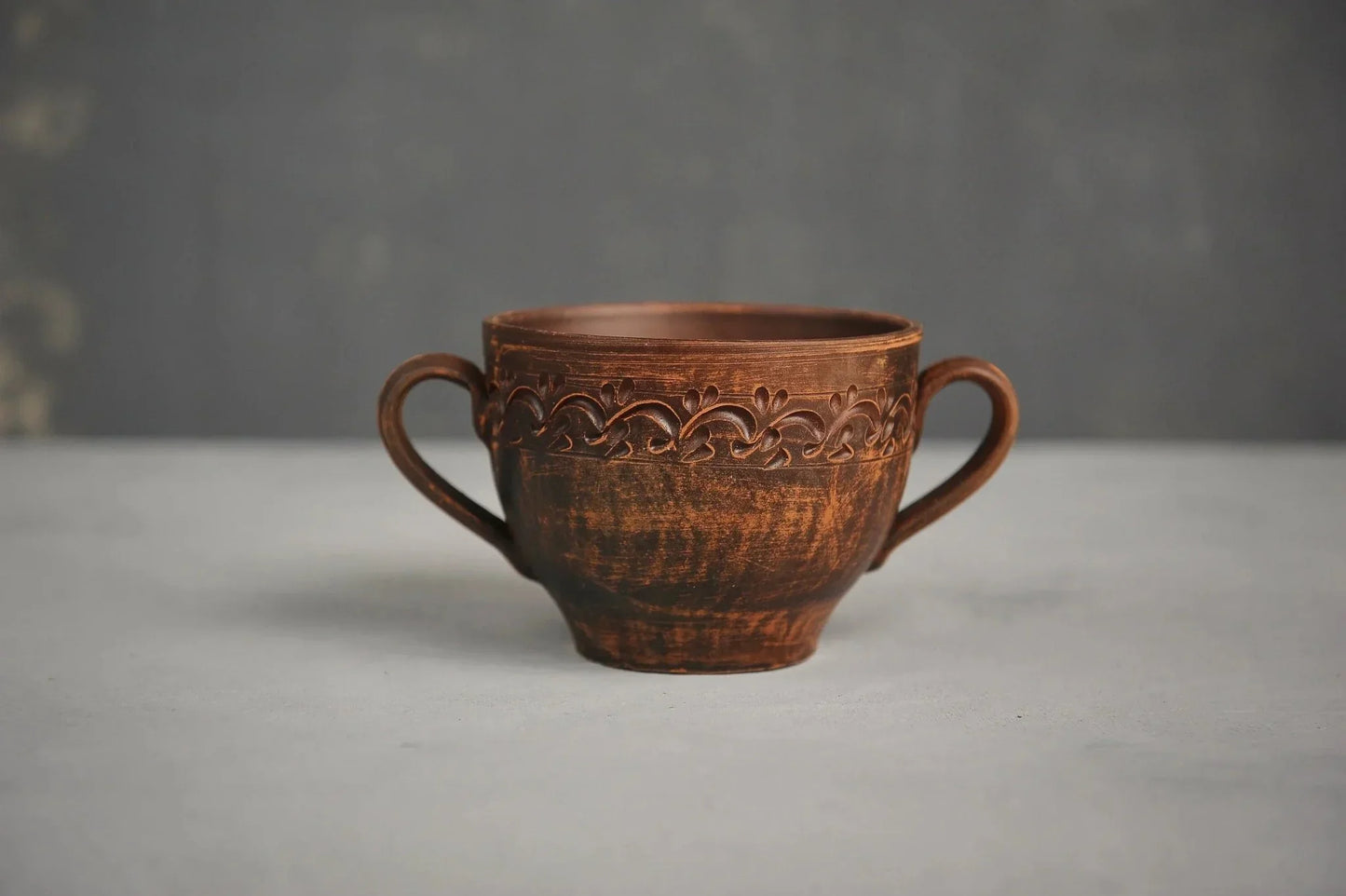 Handmade ceramic bowl with two handles and decorative pattern, rustic clay soup mug