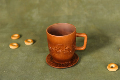 Handmade clay ceramic cup with saucer, artisan pottery mug on green background