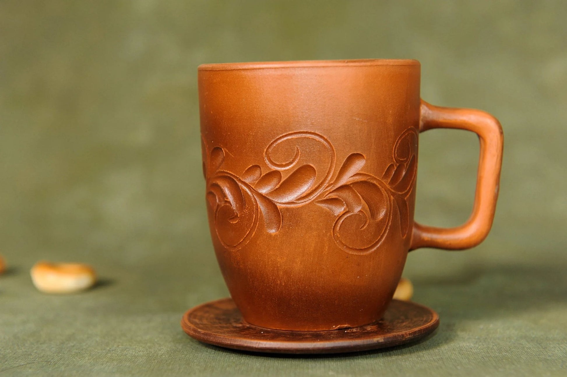 Handcrafted brown ceramic cup with embossed pattern on matching saucer, clay pottery homeware