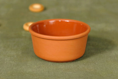 Handmade terracotta clay bowl with smooth finish on green fabric background