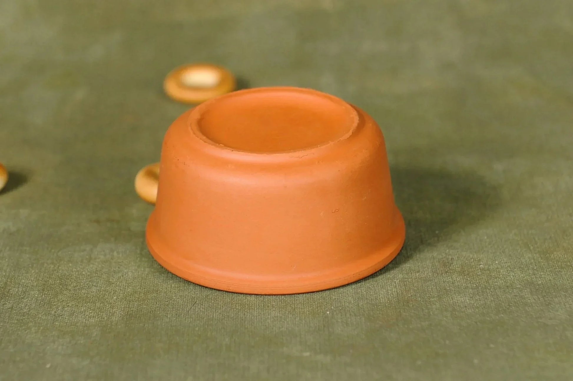 Handmade terracotta clay bowl on green fabric, artisan kitchenware from clayproductsshop
