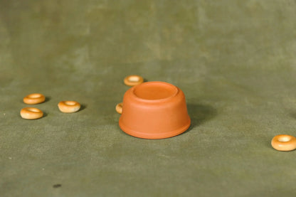 Handmade terracotta clay cupcake mold on green fabric with small round pastries