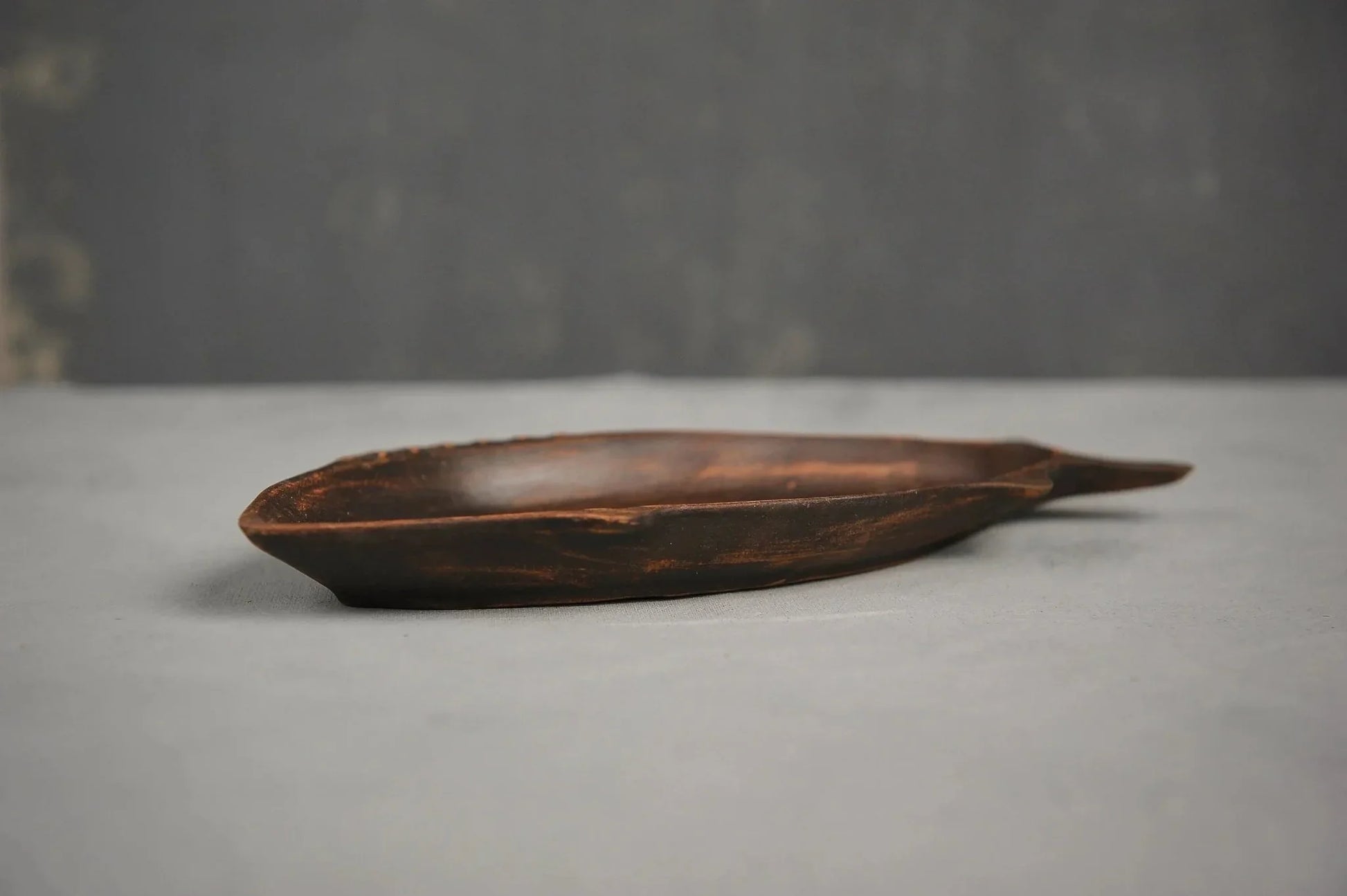 Handcrafted ceramic fish-shaped clay plate with dark brown finish on neutral background