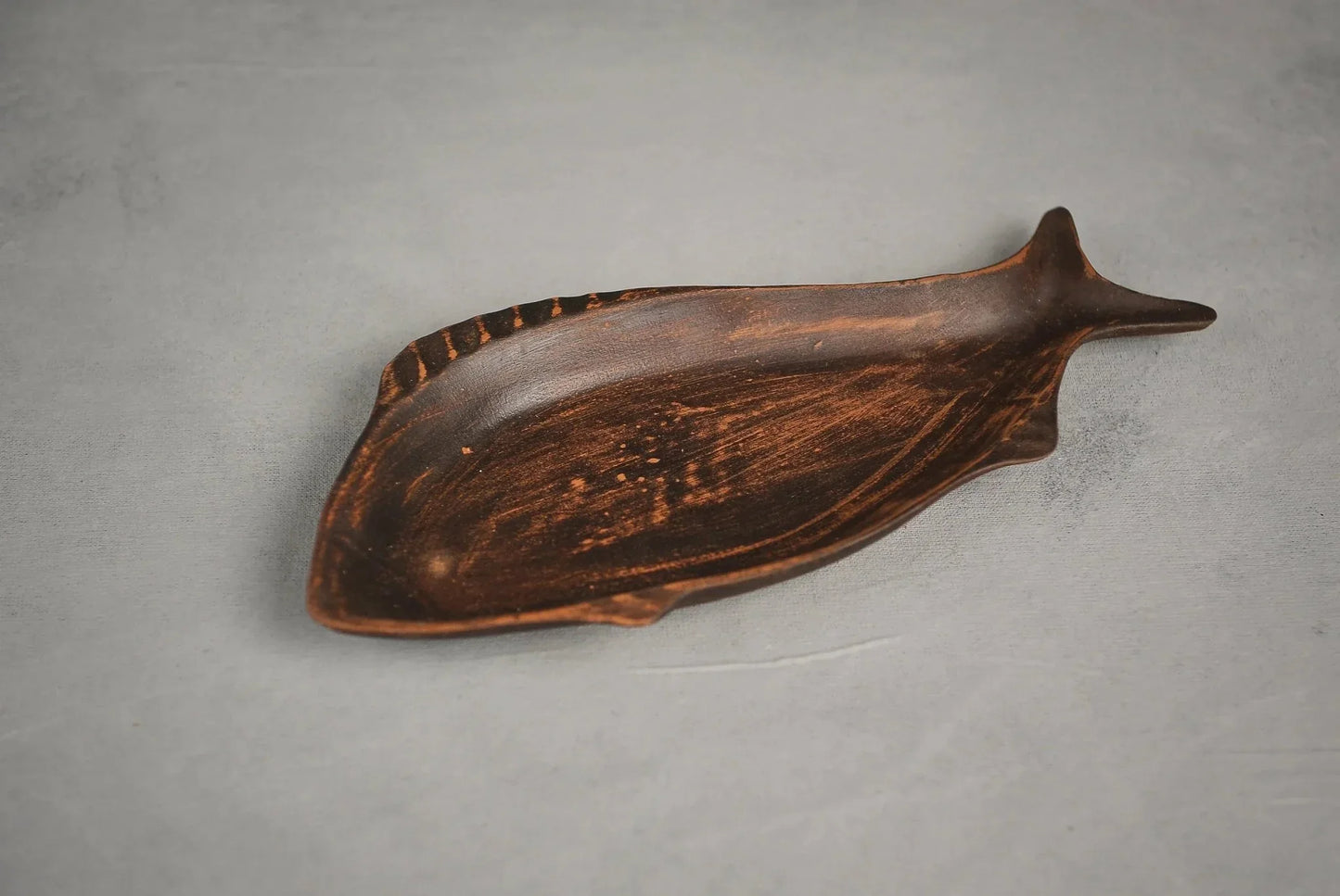Handcrafted ceramic fish-shaped clay plate on gray background, artisan home décor