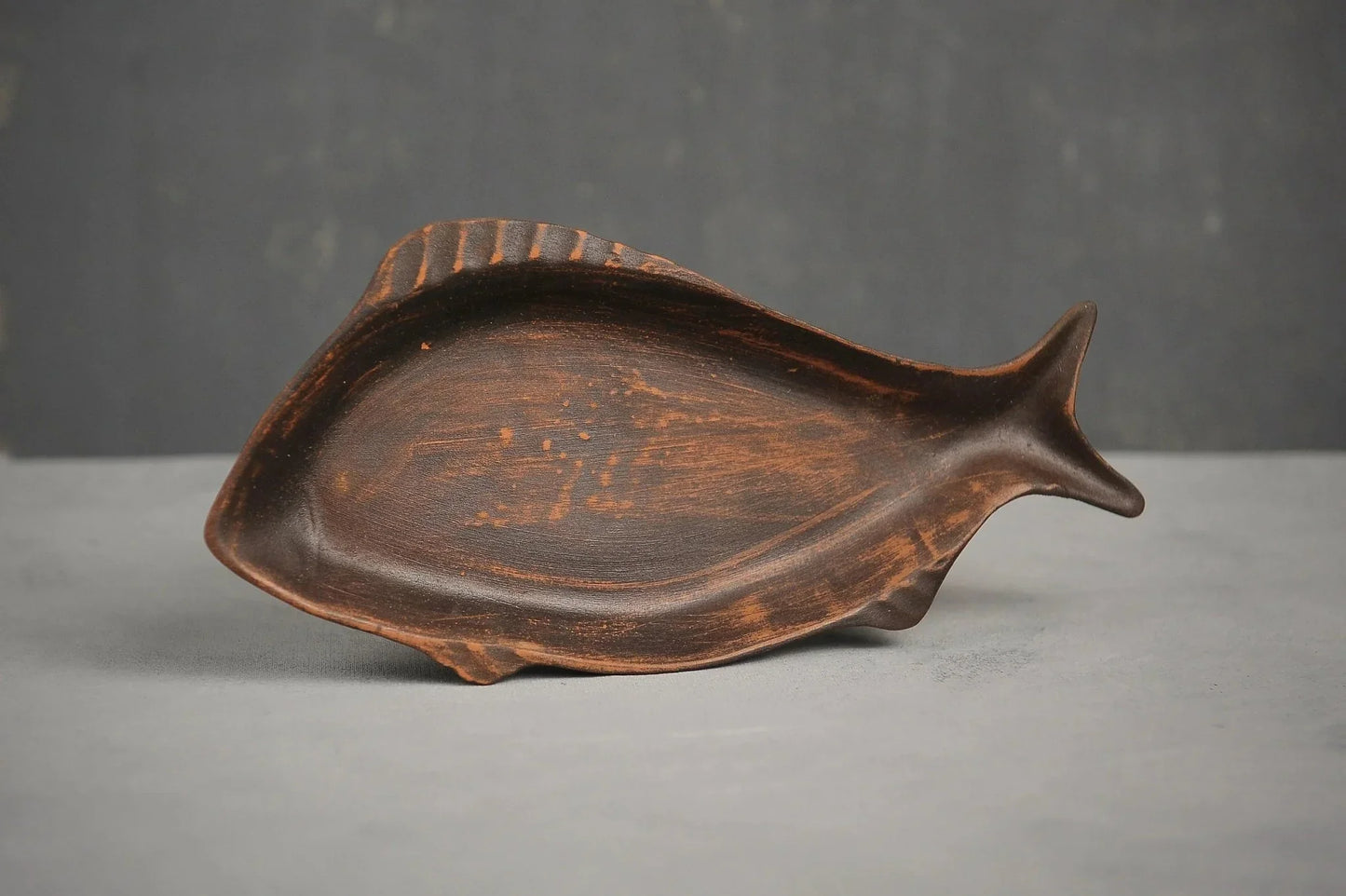 Handcrafted ceramic fish-shaped clay plate on a grey surface, artisan Ukrainian pottery
