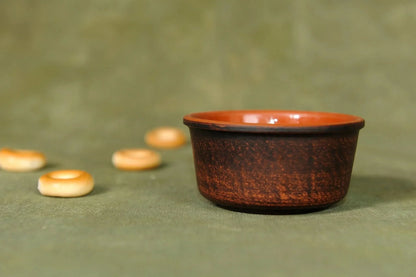 Handmade clay bowl, small brown pottery cup, artisan homeware on green fabric background