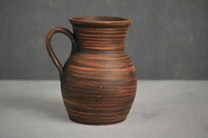 Handmade ceramic milk jug with handle, rustic brown clay pitcher on neutral background