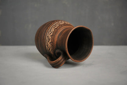 Handmade ceramic milk pitcher with hand-engraved pattern on gray surface, clay homeware