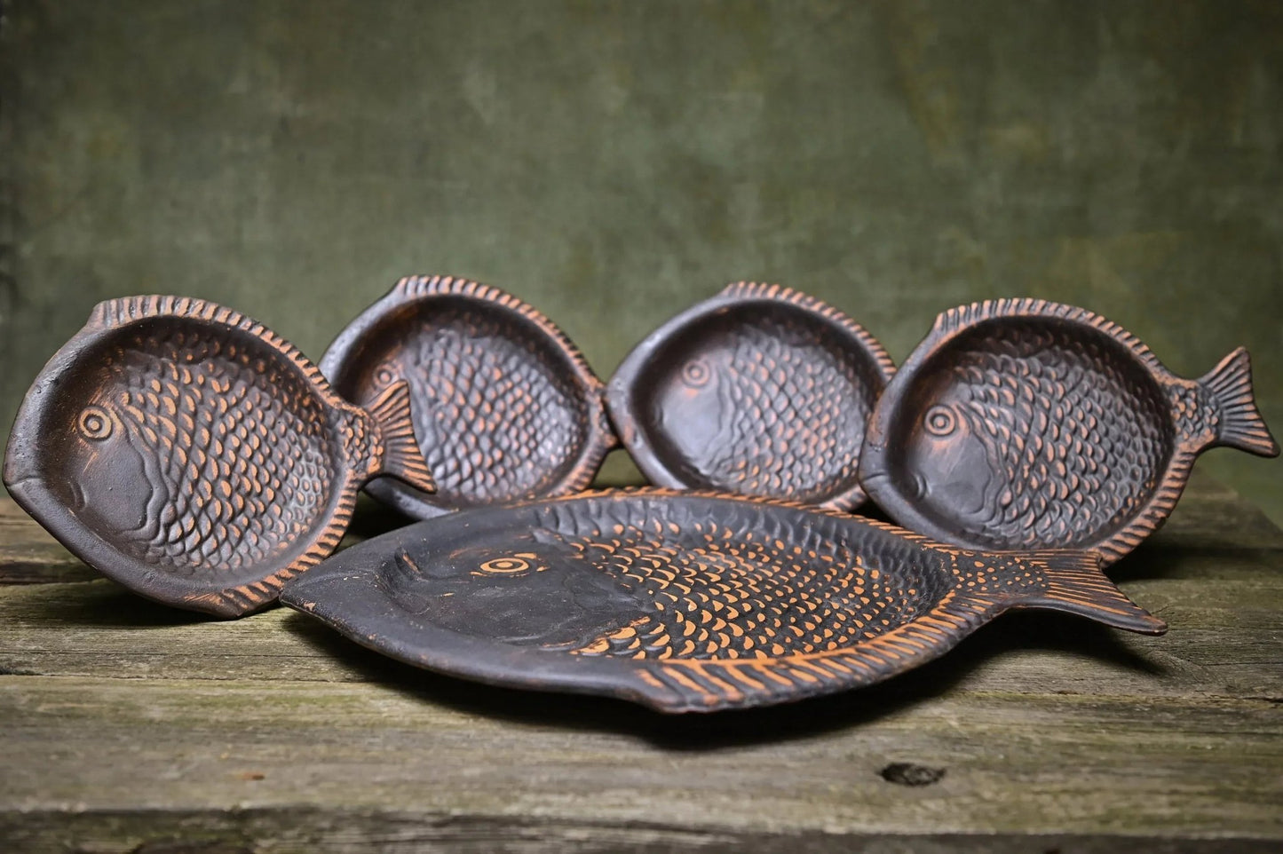 Handcrafted fish-shaped ceramic plates set on rustic wood, artisan clay homeware