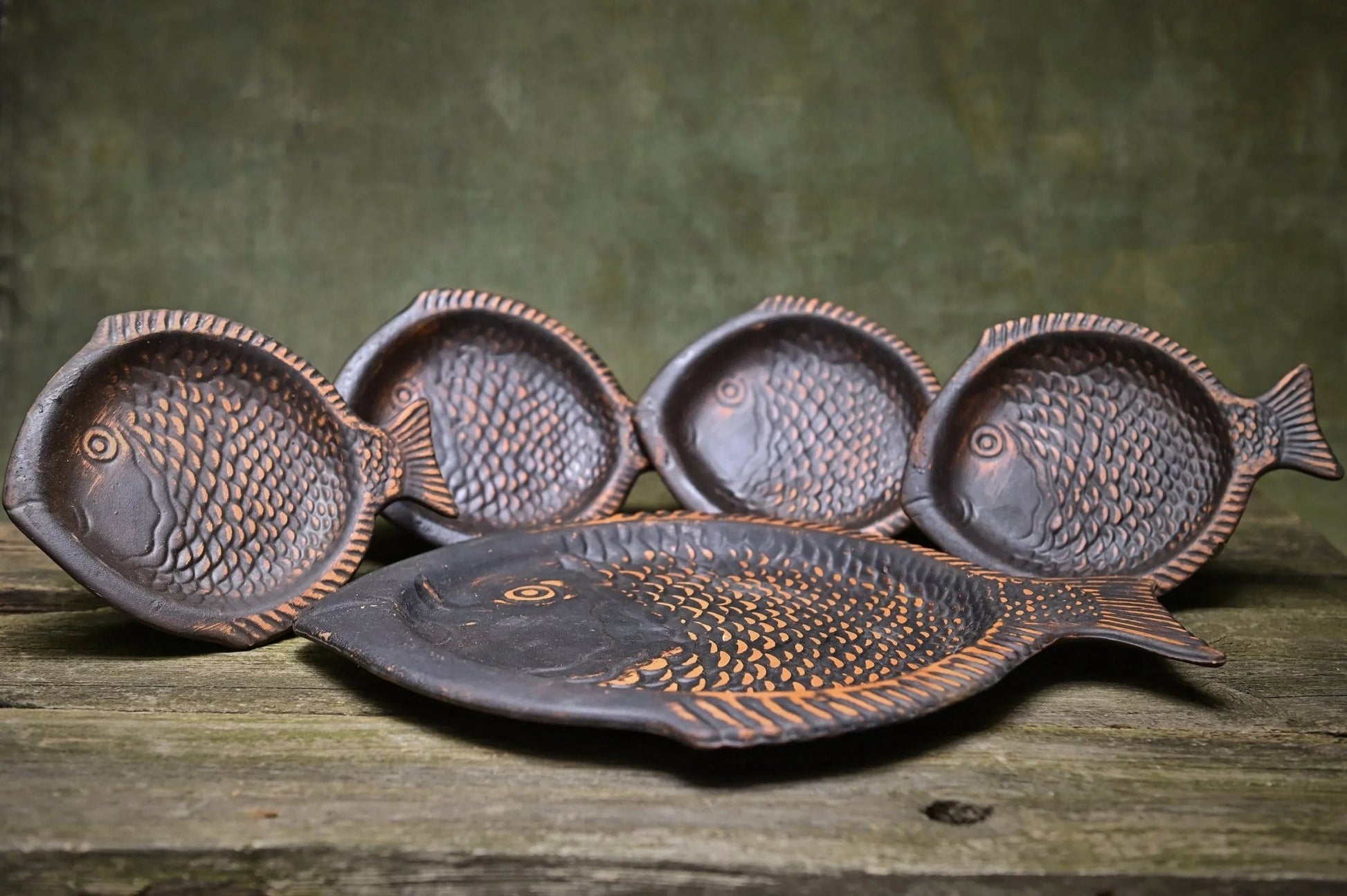 Handcrafted fish-shaped ceramic plates set on rustic wood, artisan clay homeware