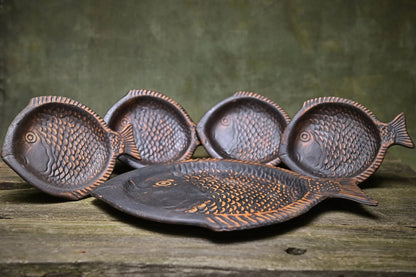 Handcrafted fish-shaped ceramic plates set on rustic wood, artisan clay homeware