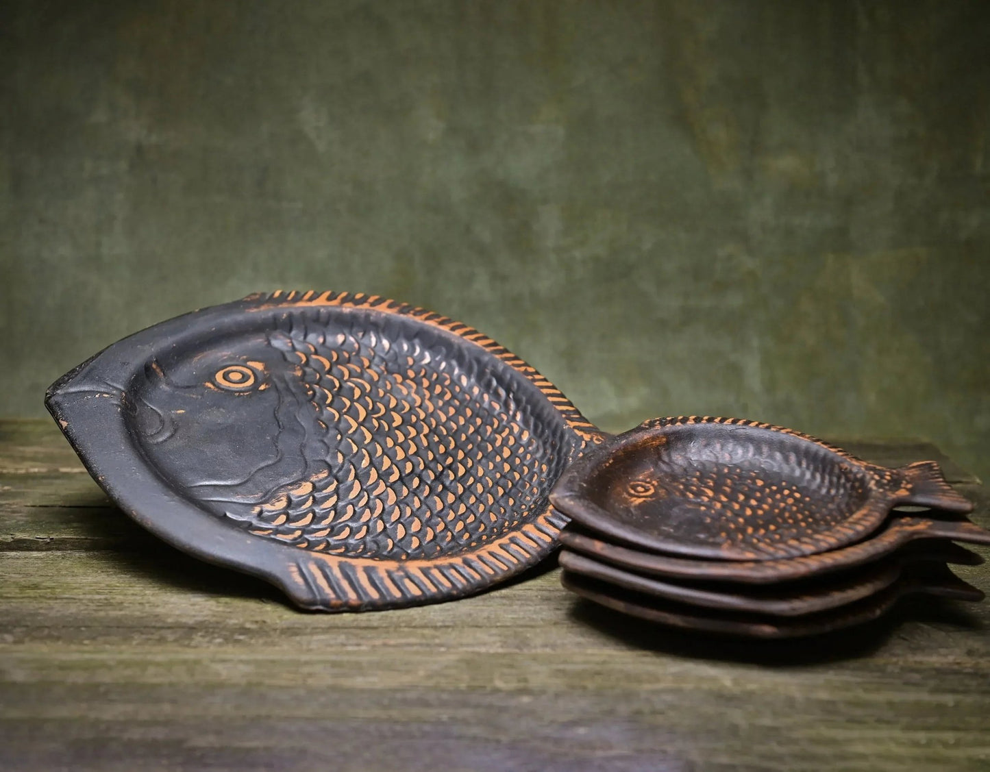 Handcrafted clay fish-shaped ceramic plates set, artisan pottery dishes on wooden surface