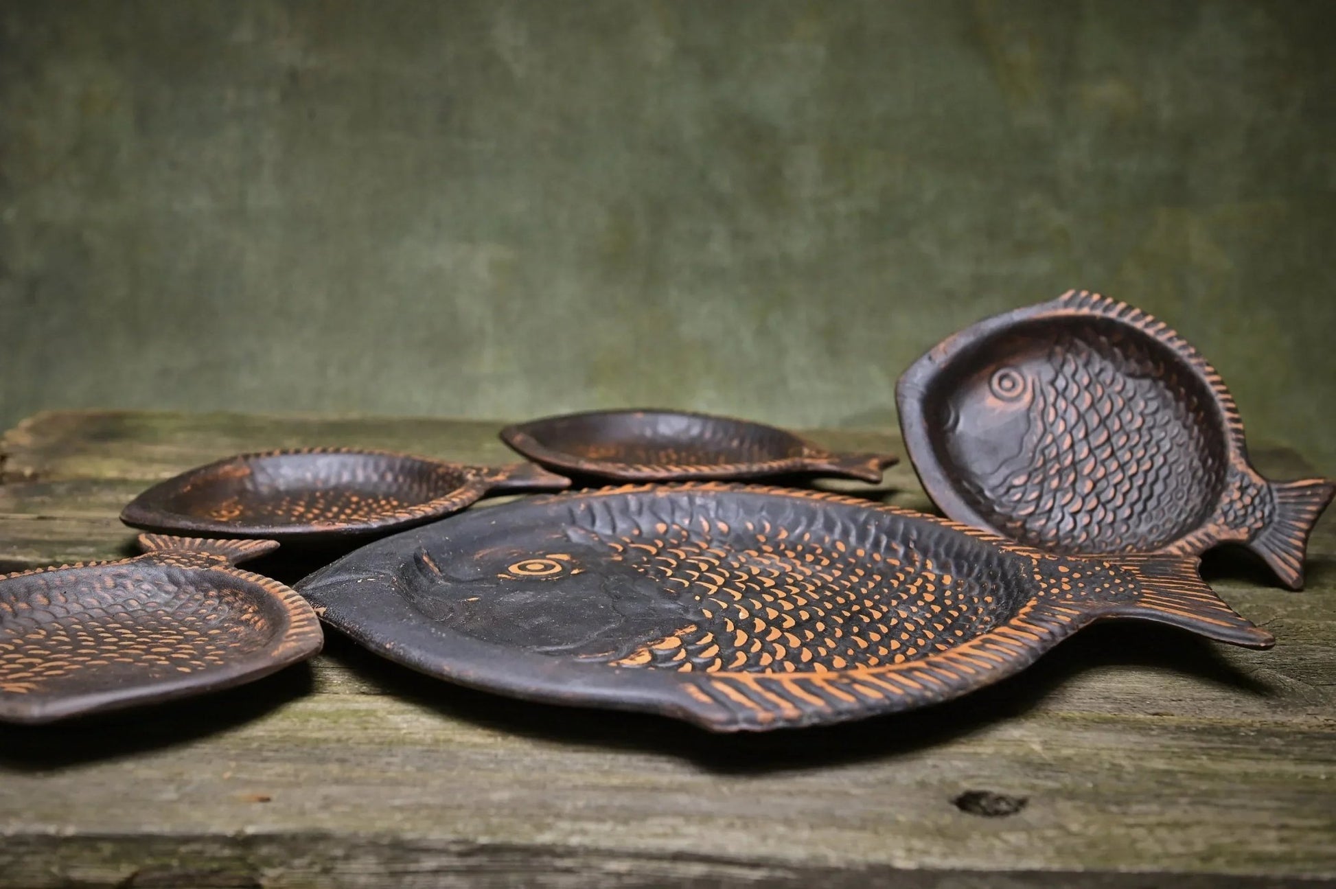 Handmade ceramic fish-shaped clay plates set on rustic wood surface, artisan homeware