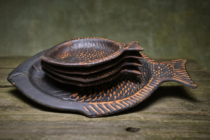 Handmade ceramic fish-shaped plates set on rustic wood, artisan clay homeware