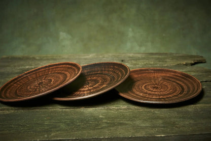 Set of three handmade ceramic plates with rustic brown glaze on a wooden table