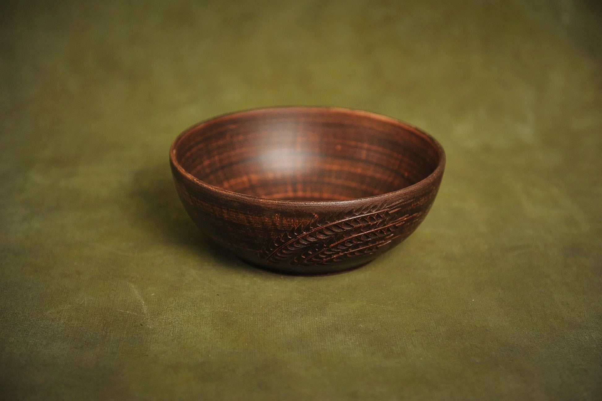 Handmade rustic ceramic clay salad bowl with leaf engraving on green background