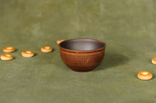 Handmade rustic ceramic dipping bowl with brown glaze on green backdrop, clayproductsshop