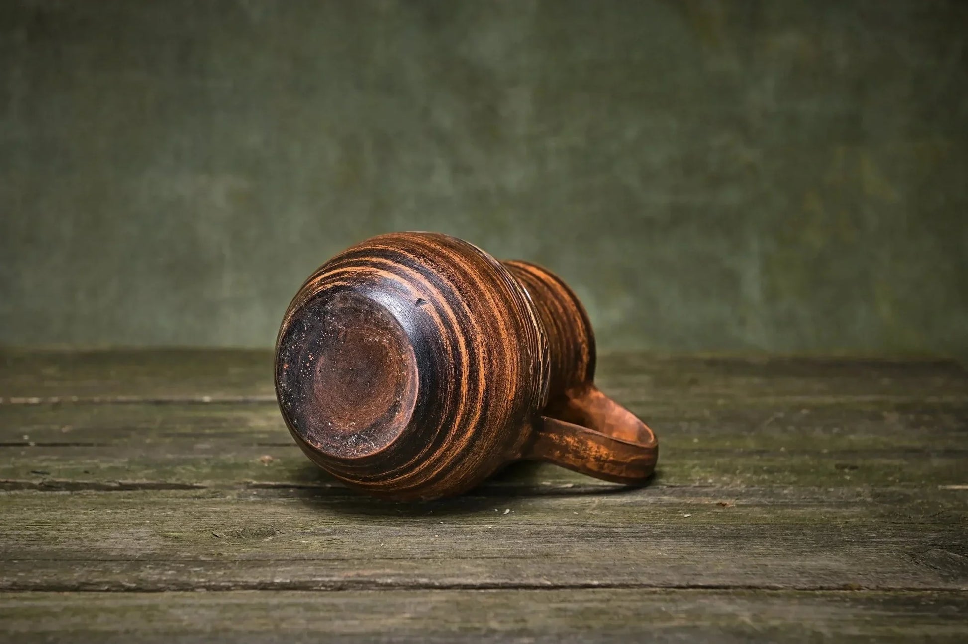 Handmade clay creamer jug with rustic brown finish on wooden surface, artisan pottery homeware