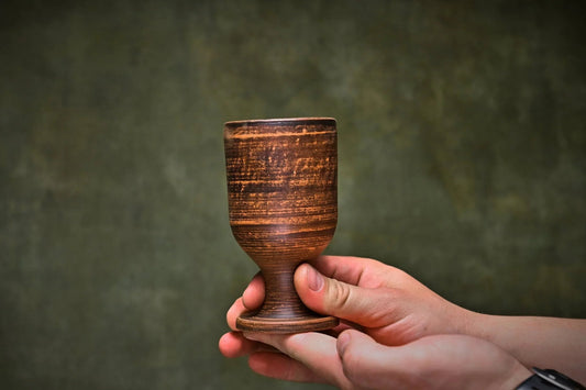 Handmade rustic clay wine goblet held in hand, artisan pottery from clayproductsshop