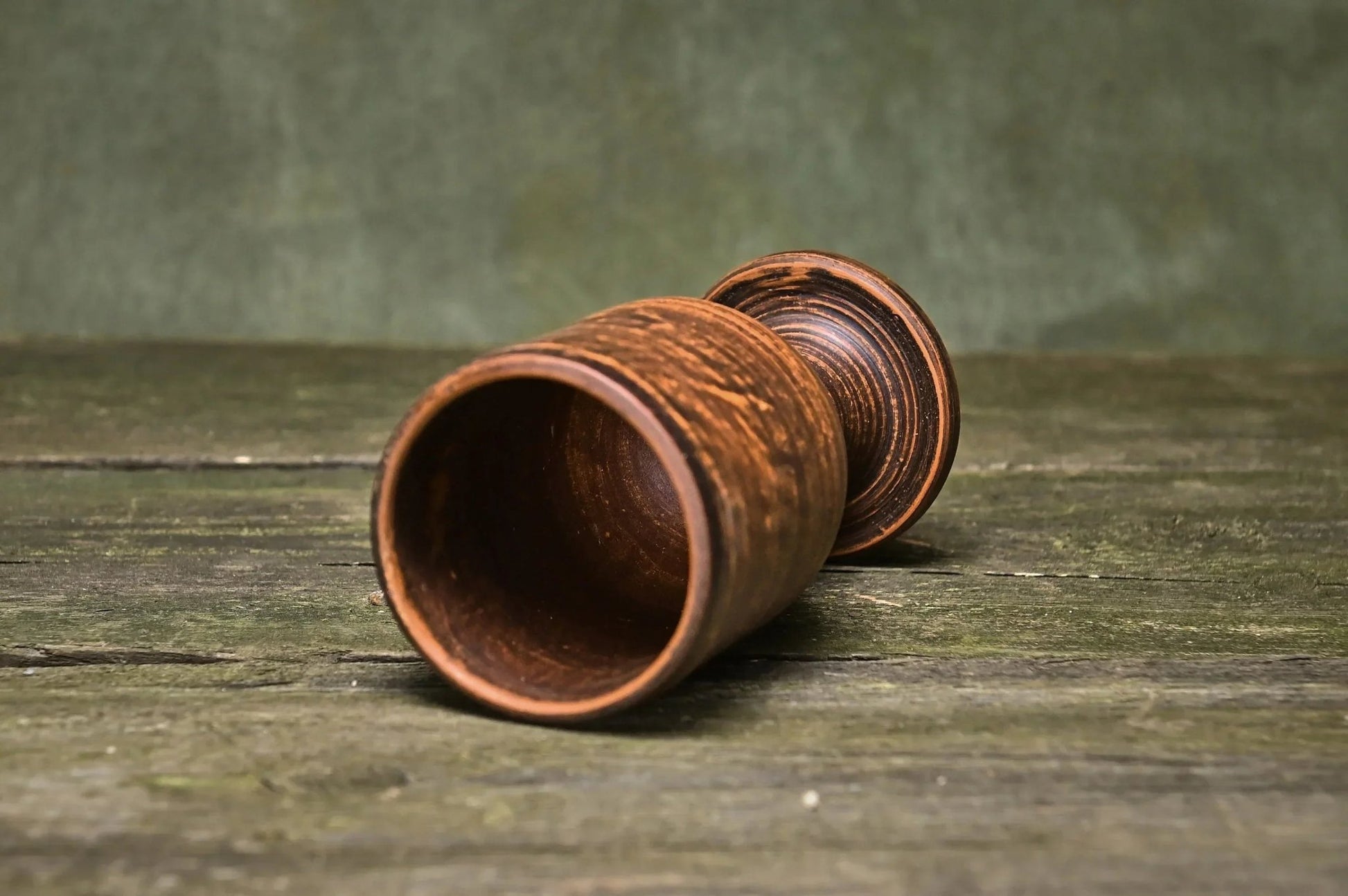Handmade clay wine goblet with rustic finish on a wooden surface, artisan tableware
