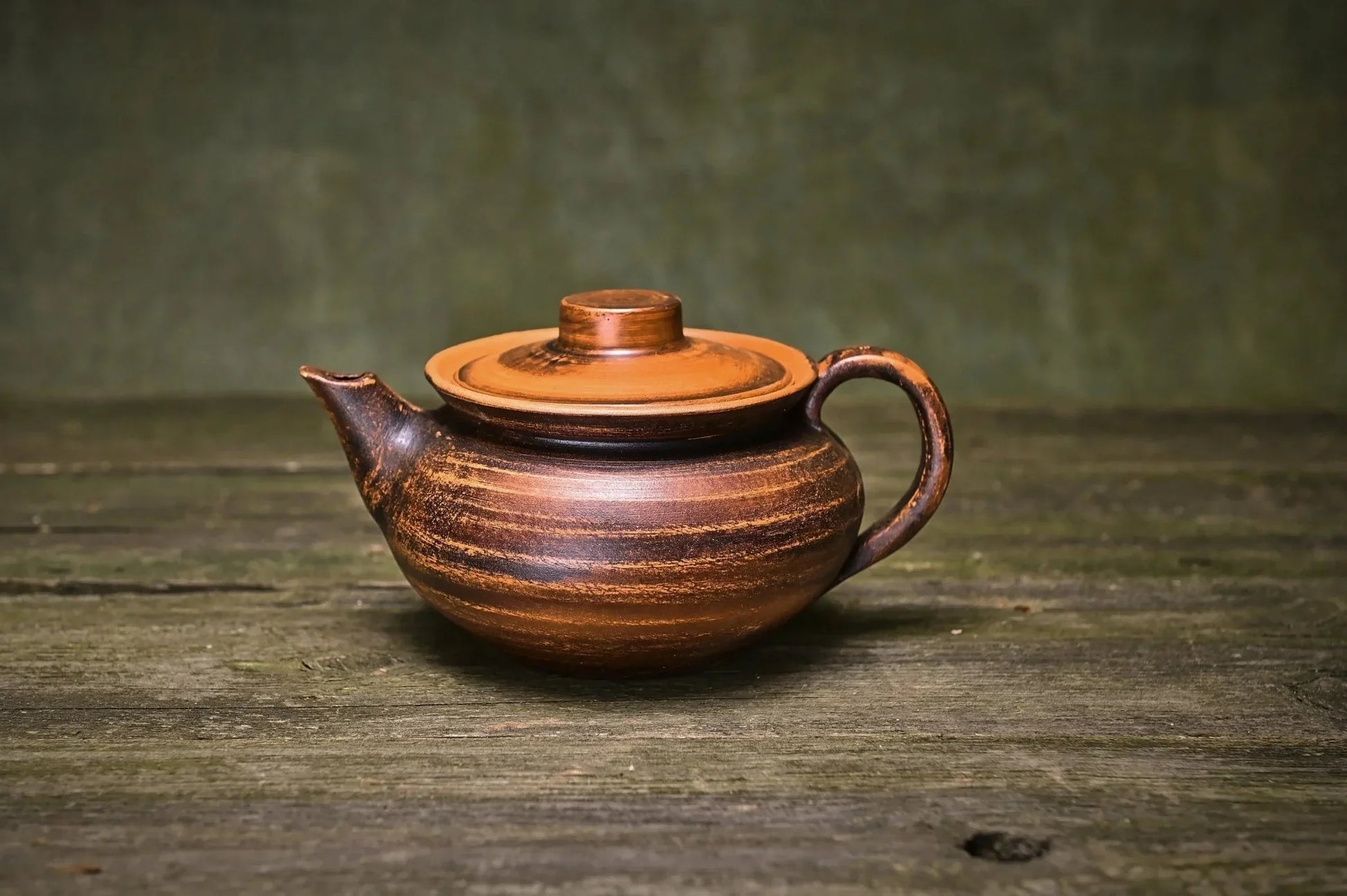 Handmade clay teapot with rustic brown finish on a wooden surface, artisan home decor