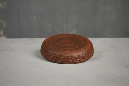 Handmade brown clay plate with hand-engraved design on a gray background, artisan homeware