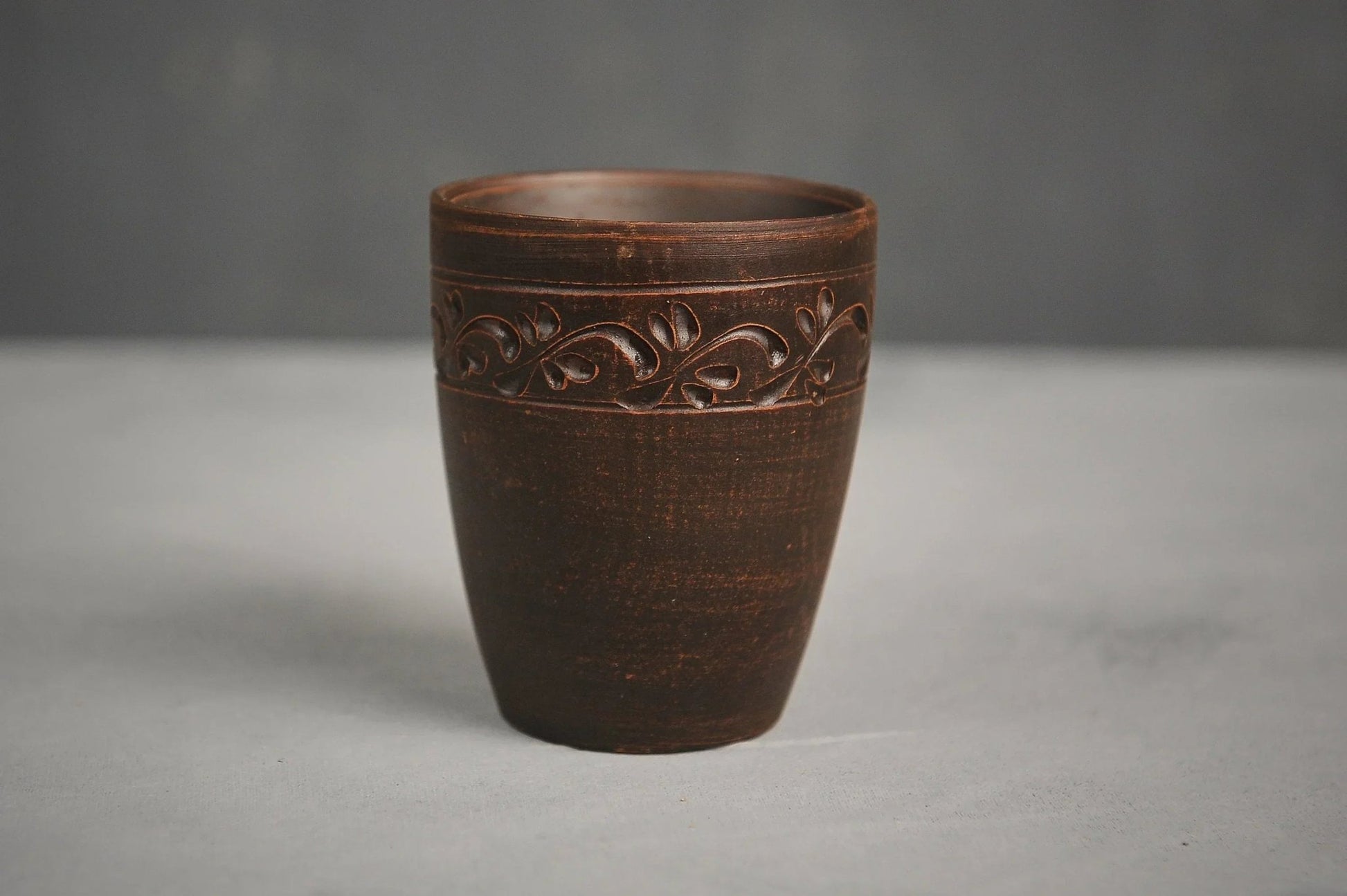Hand-engraved ceramic drinking glass made of red clay with leaf motif, artisan homeware