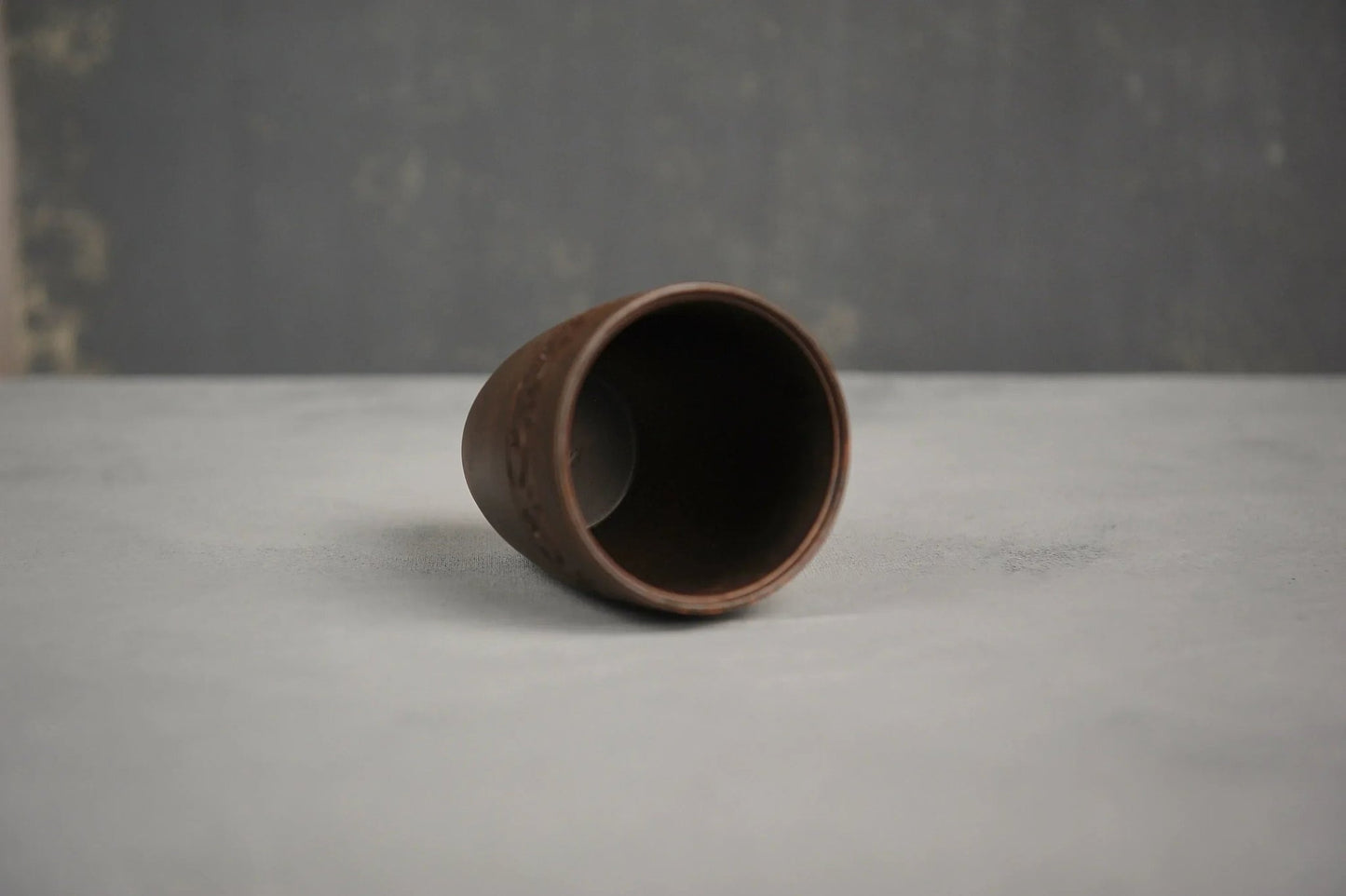 Hand-engraved ceramic red clay drinking glass on a light surface, artisan homeware