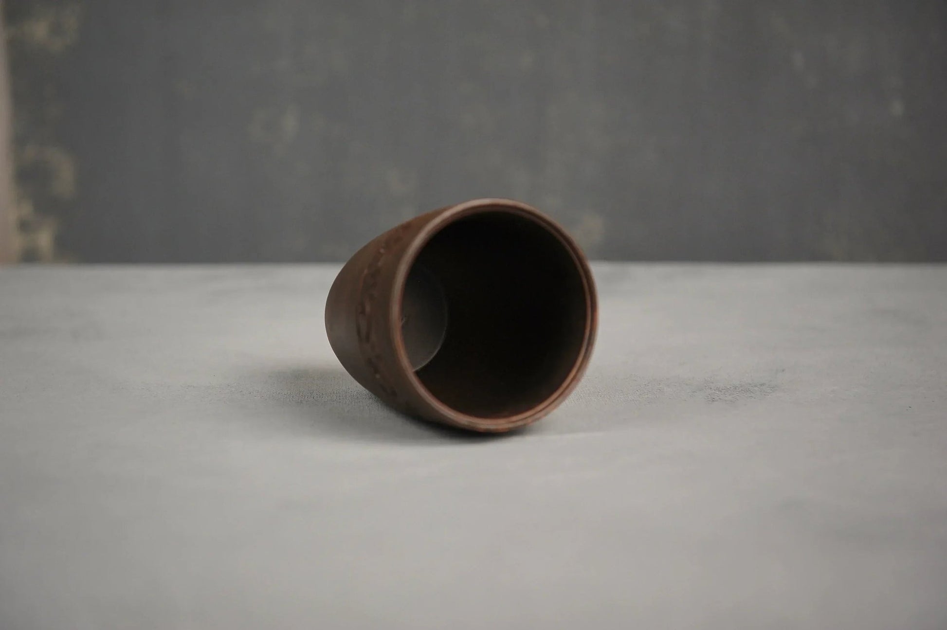 Hand-engraved ceramic red clay drinking glass on a light surface, artisan homeware