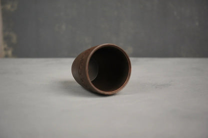 Hand-engraved ceramic red clay drinking glass on a light surface, artisan homeware