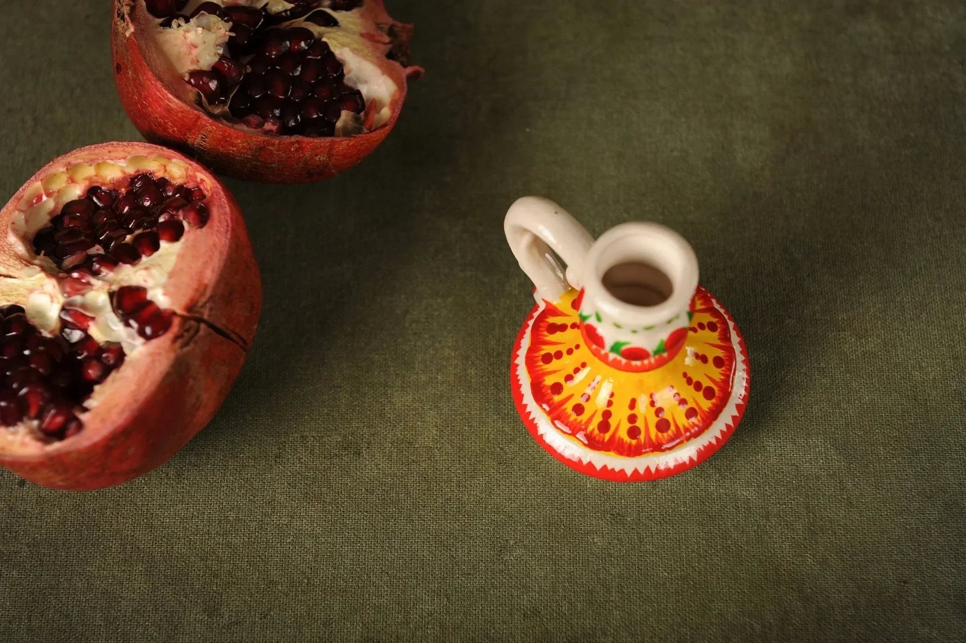 Hand-painted ceramic candlestick on green fabric with pomegranate, artisan clay home decor