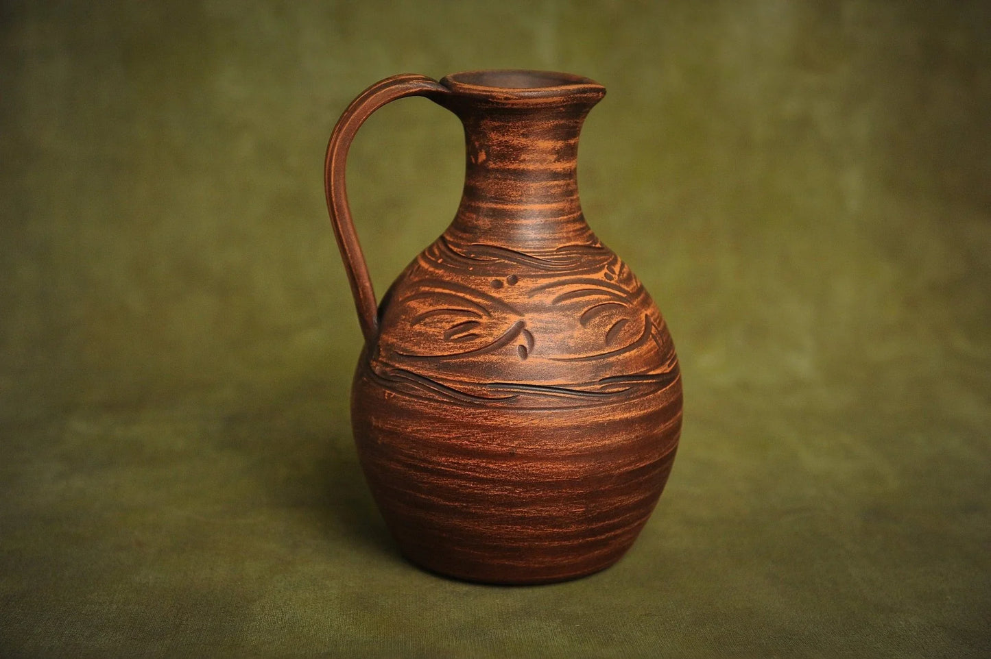 Handcrafted ceramic clay jug with carved patterns, artisan homeware on neutral background