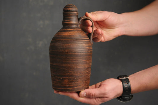 Handmade red clay bottle with lid and handle, rustic artisan jug for home decor