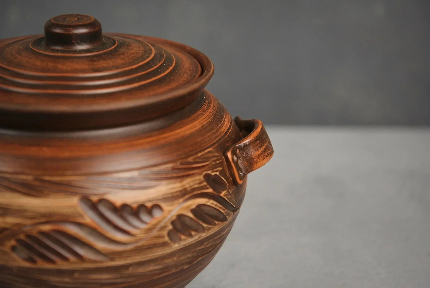 Handmade ceramic pot with lid and handles, brown artisanal clay cookware, leaf pattern