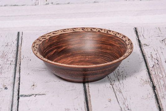 Handmade clay bowl with rustic pattern, artisan ceramic homeware on white wooden surface