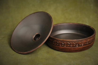 Handmade clay cooking pot with lid, organic ceramic bakeware on green background