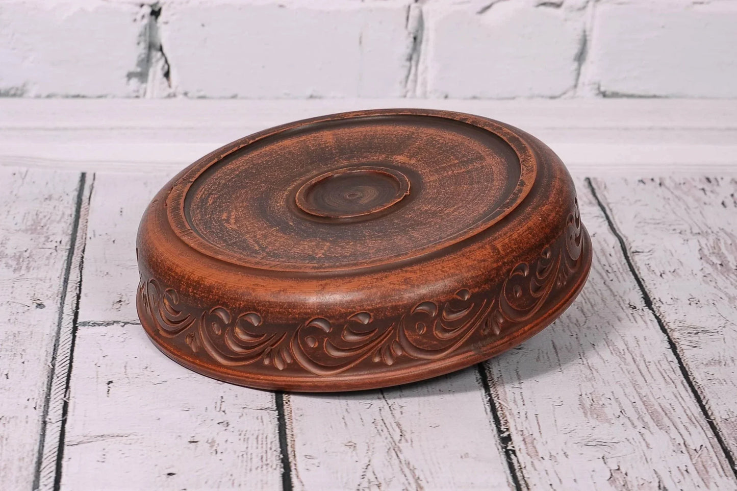 Handmade clay pancake maker plate with carved design, rustic ceramic tray on wood surface